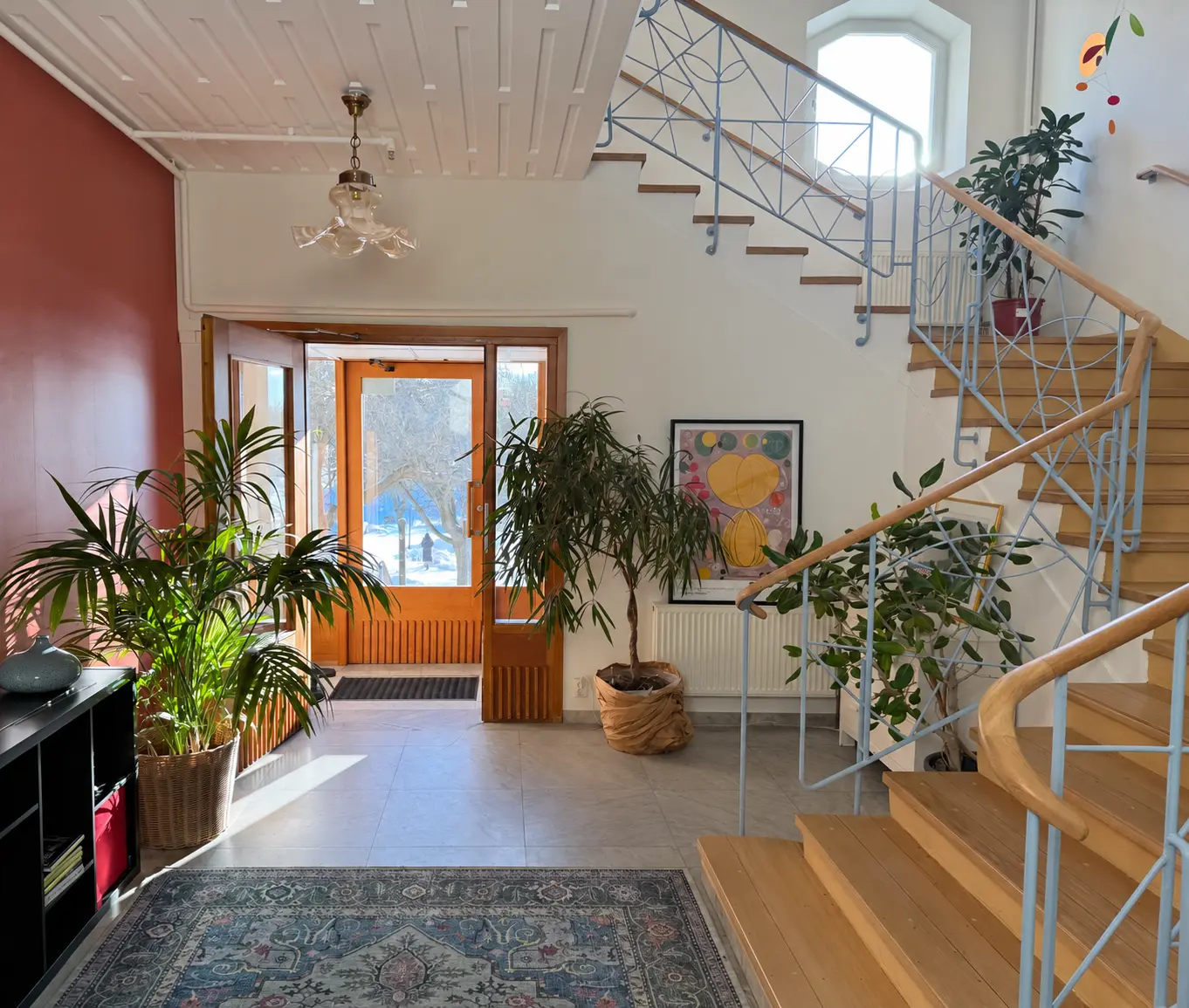The entrance hall at Lakefront, with its wooden staircase and indoor plants.